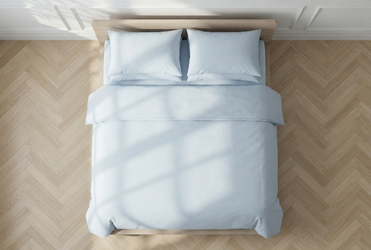 Light blue organic bedding set on a bed with wooden floor and white walls. House of March