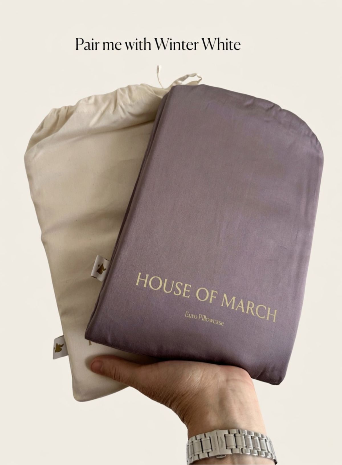 Hand holding plum and winter white bed linens from House of March