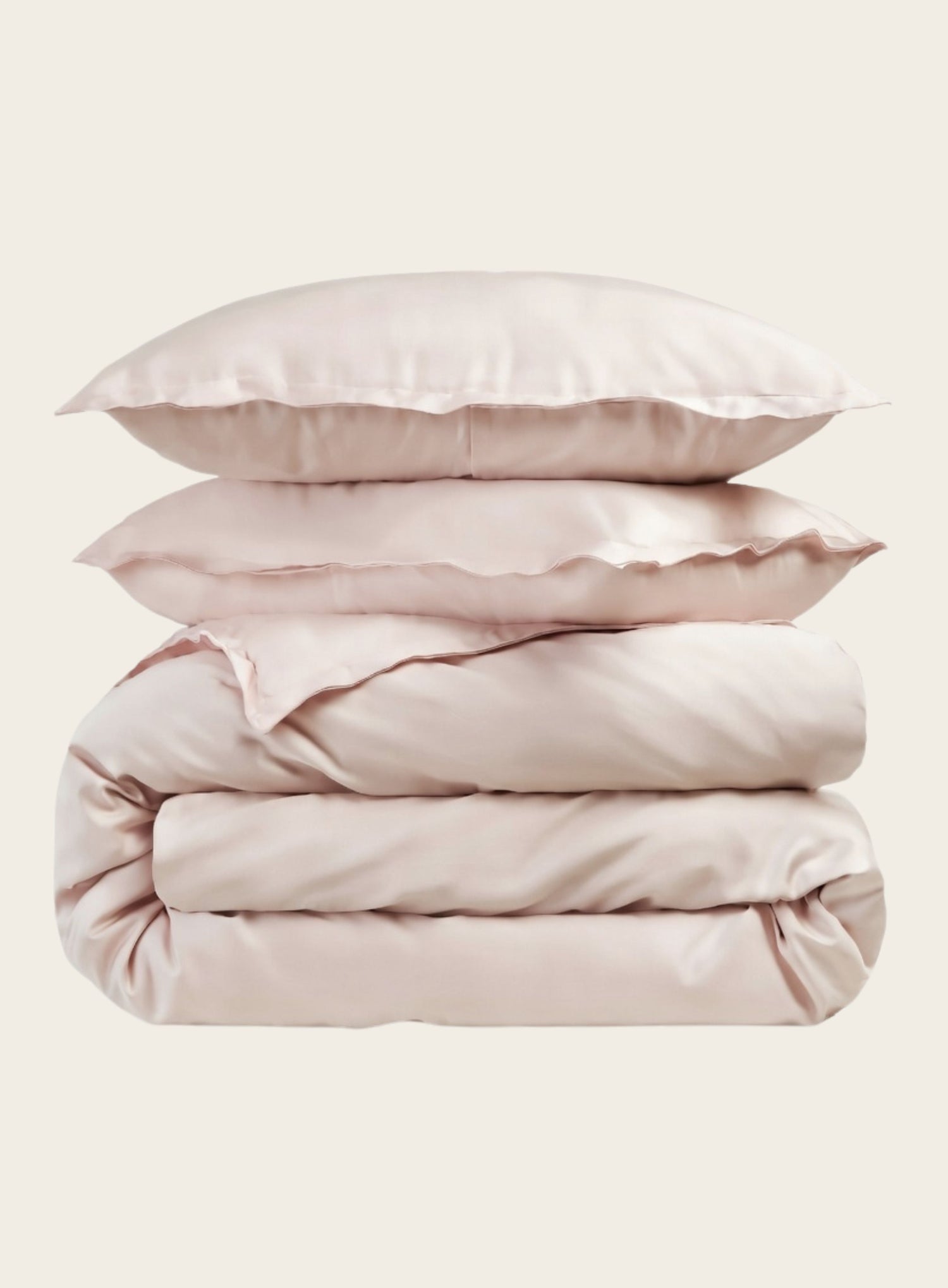 Stack of house of march blush organic bedding with pillows on a light beige background