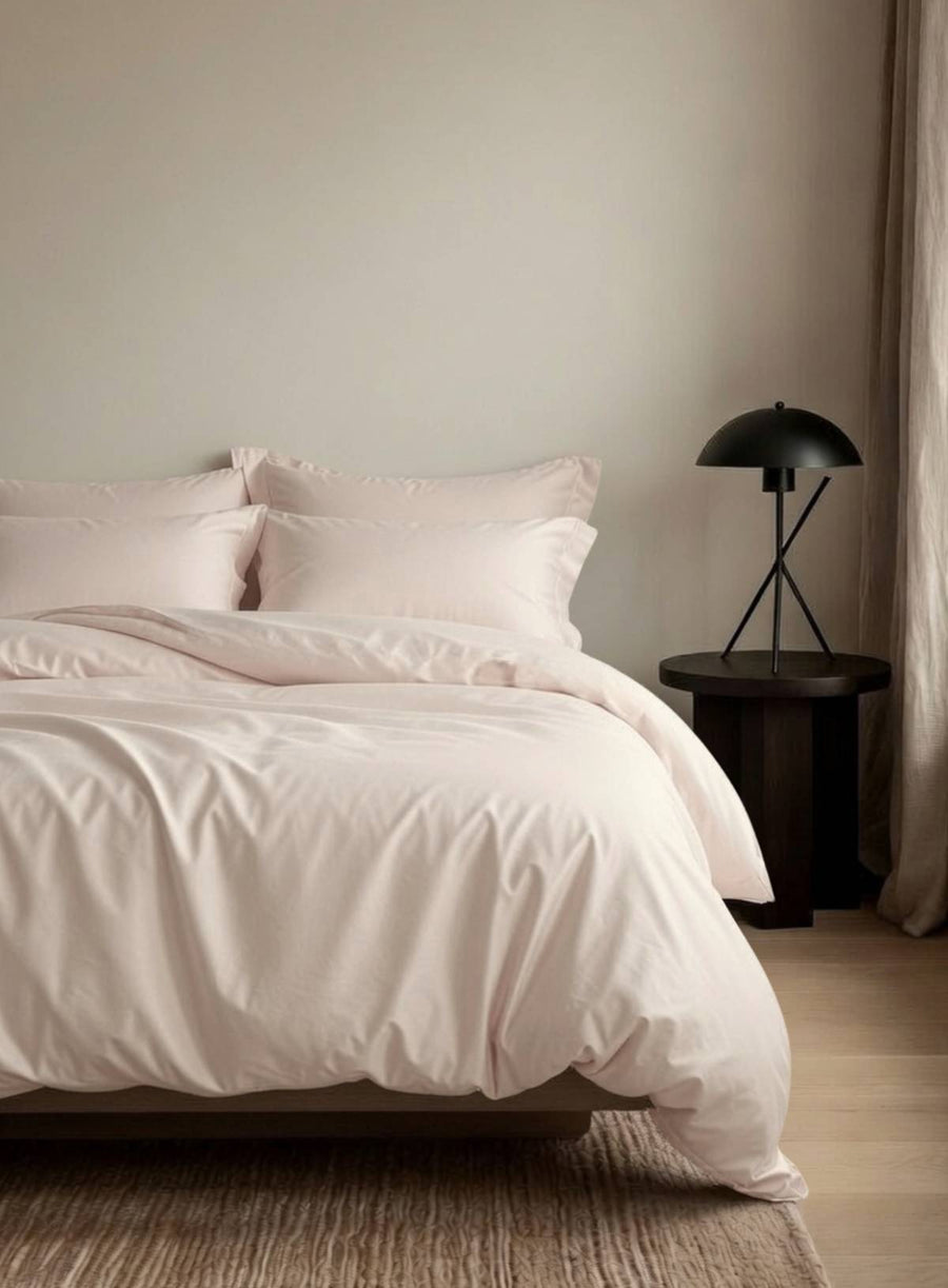 Neatly made bed with a light pink organic duvet cover
