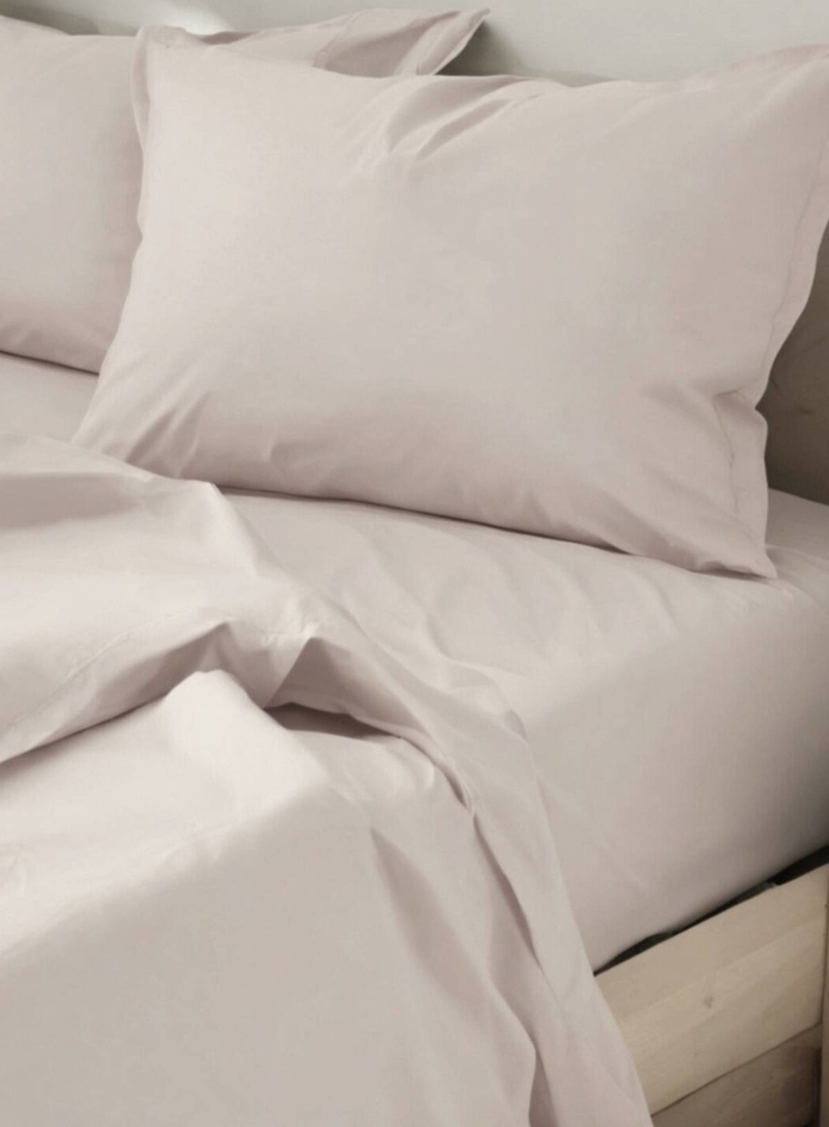 Neatly made bed with light-colored PINK bedding and pillows.