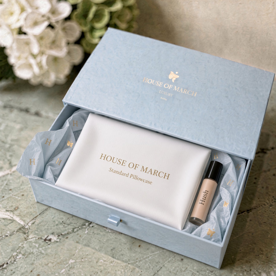 A light blue House of March gift box opened to reveal a white Standard Pillcase and a pulse point roller.