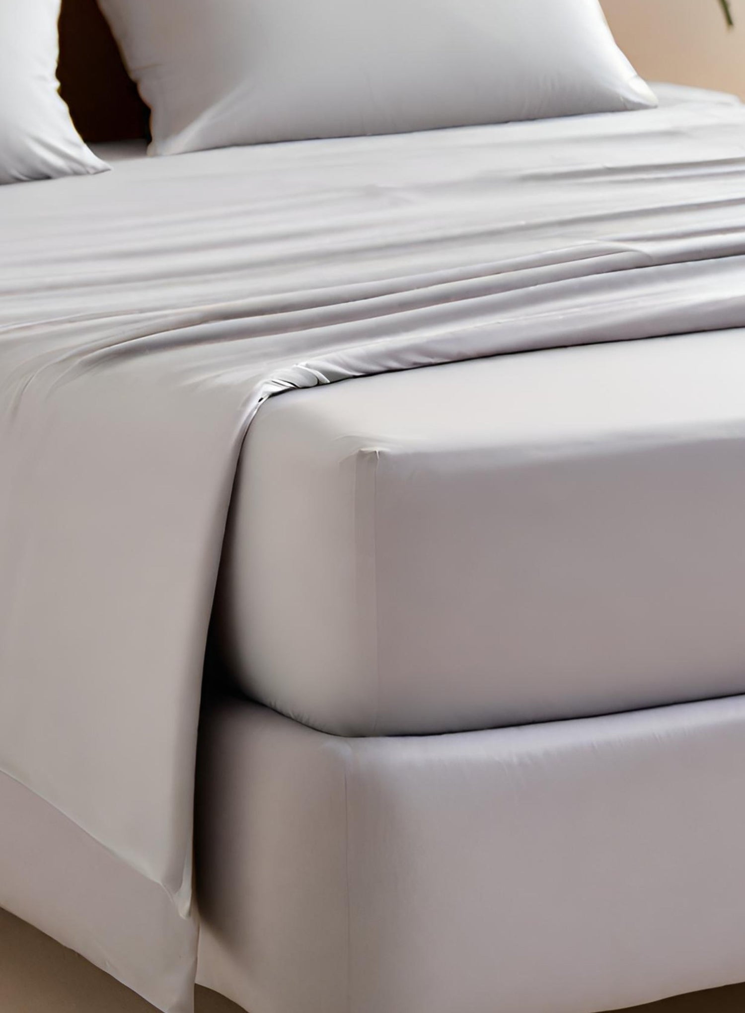 A fitted sheet in a pebble colour displayed on a bed.