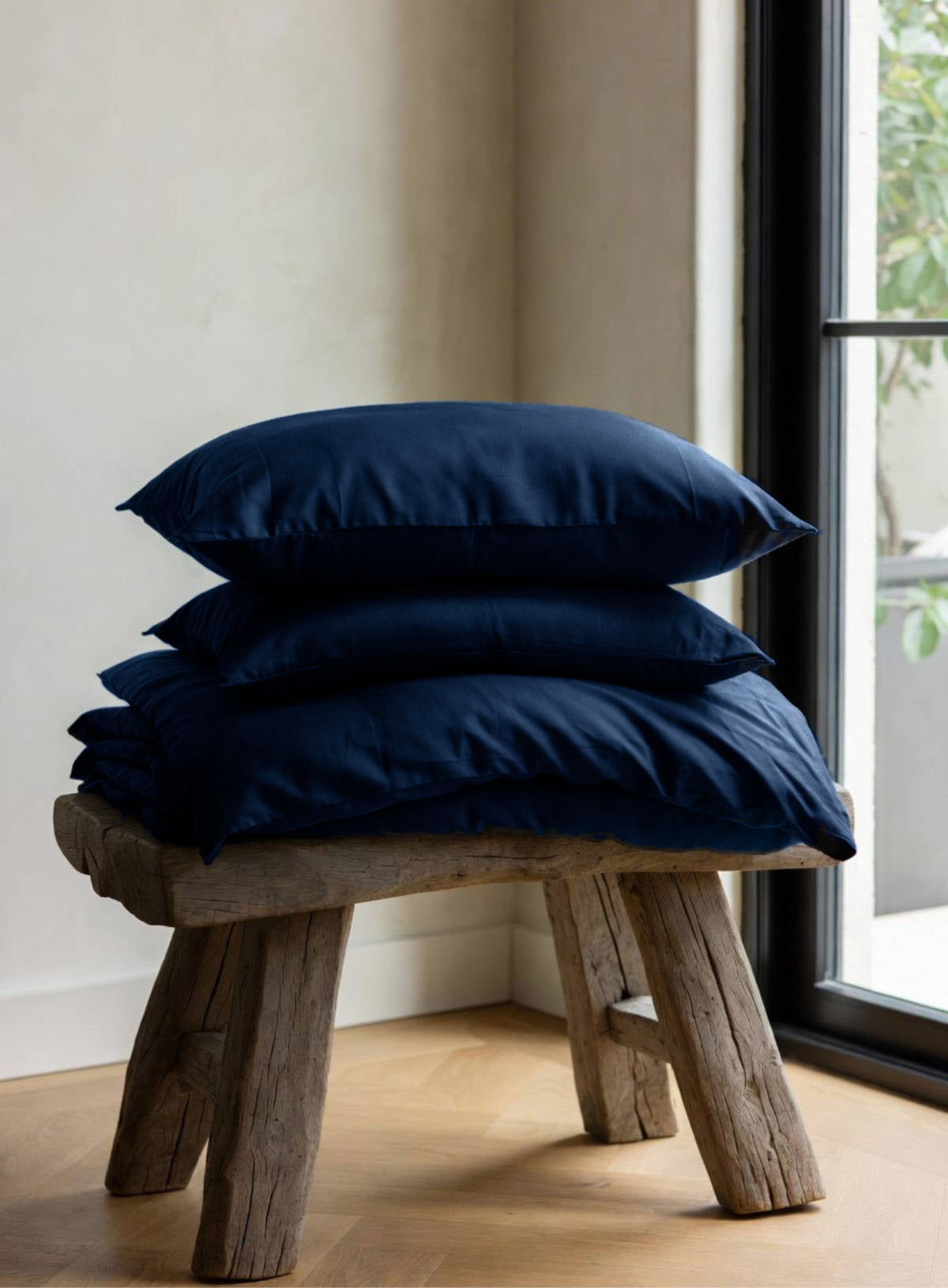 House of March Ink Blue organic cotton a pile of ink blue bedding on a wooden stool