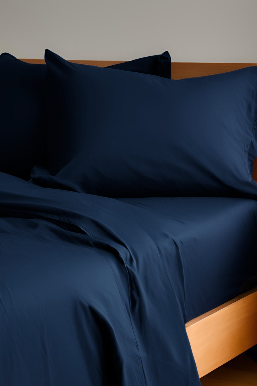 House of March Ink Blue organic cotton a hemmed pillowcase pair on a bed with ink blue sheets