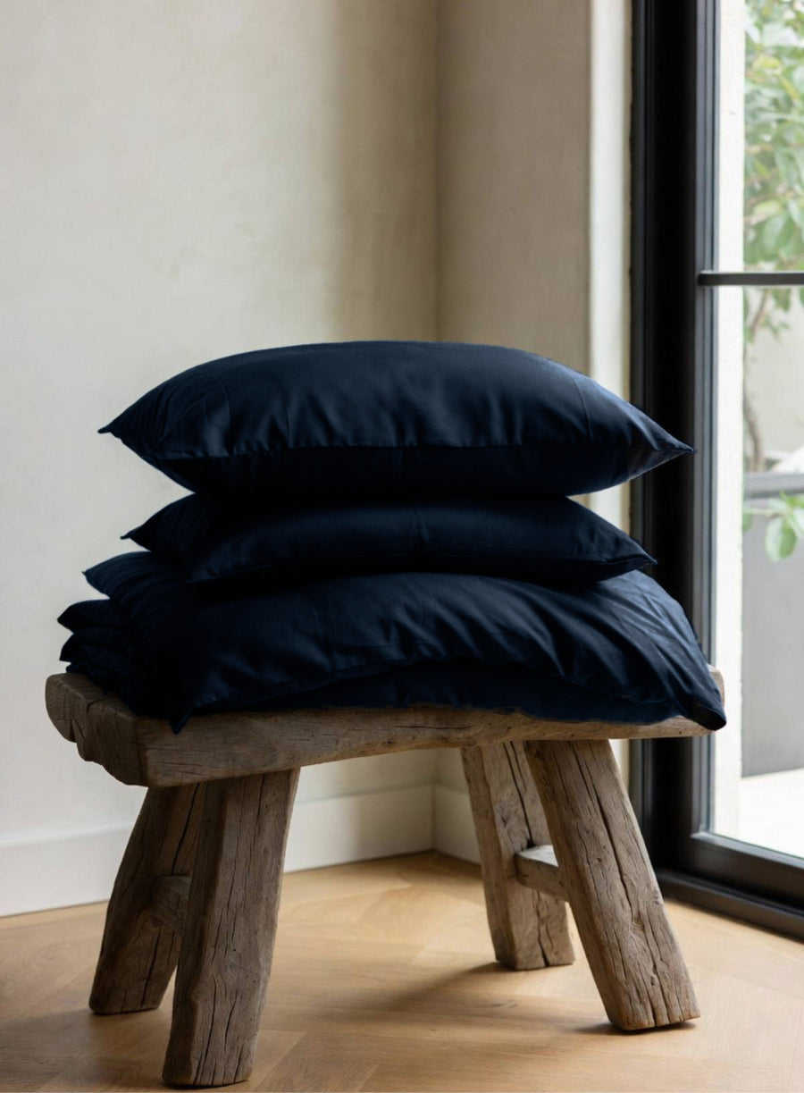 House of March Navy 2026 organic cotton bedding pile on a wooden stool