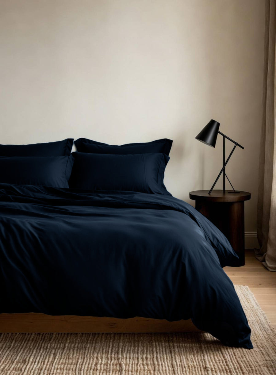 House of March Navy 2026 organic cotton duvet cover on a bed with a bedside lamp