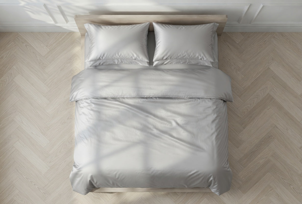 Gray bedding set on a bed with a wooden headboard in a room with wooden flooring.