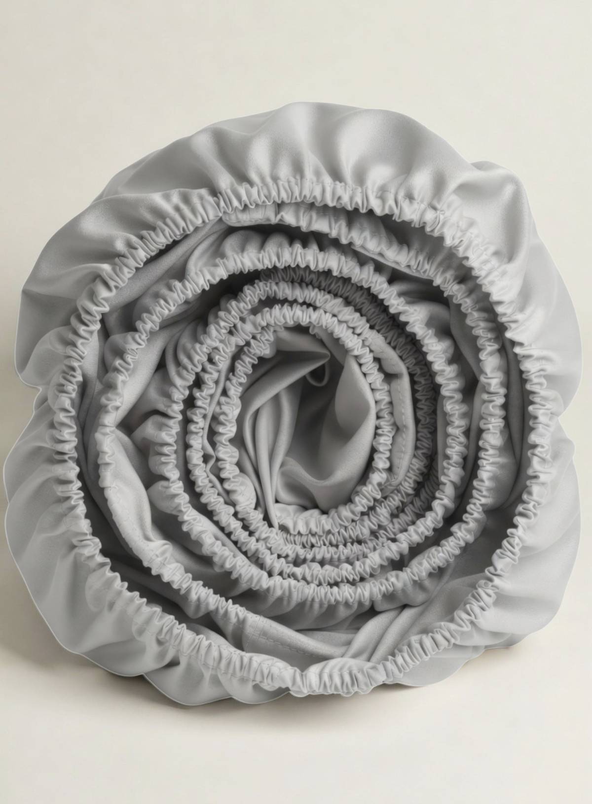 A rolled up fitted sheet in pebble silvery grey