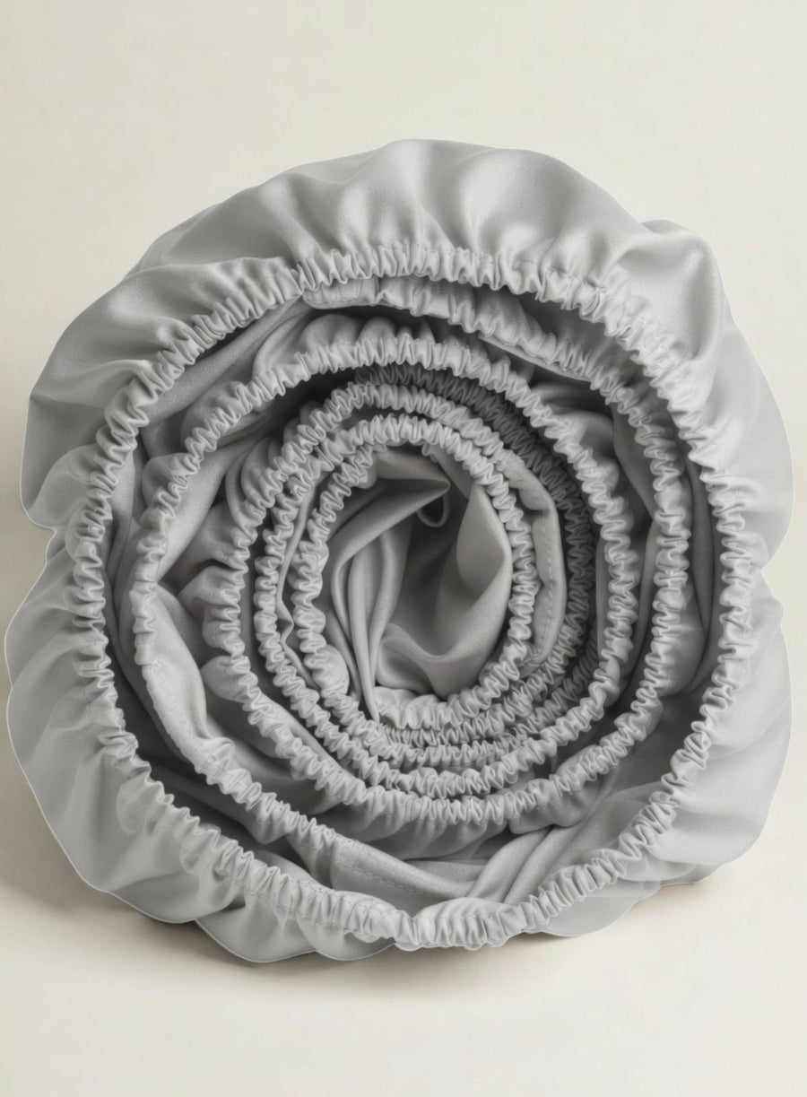 A rolled up fitted sheet in pebble silvery grey