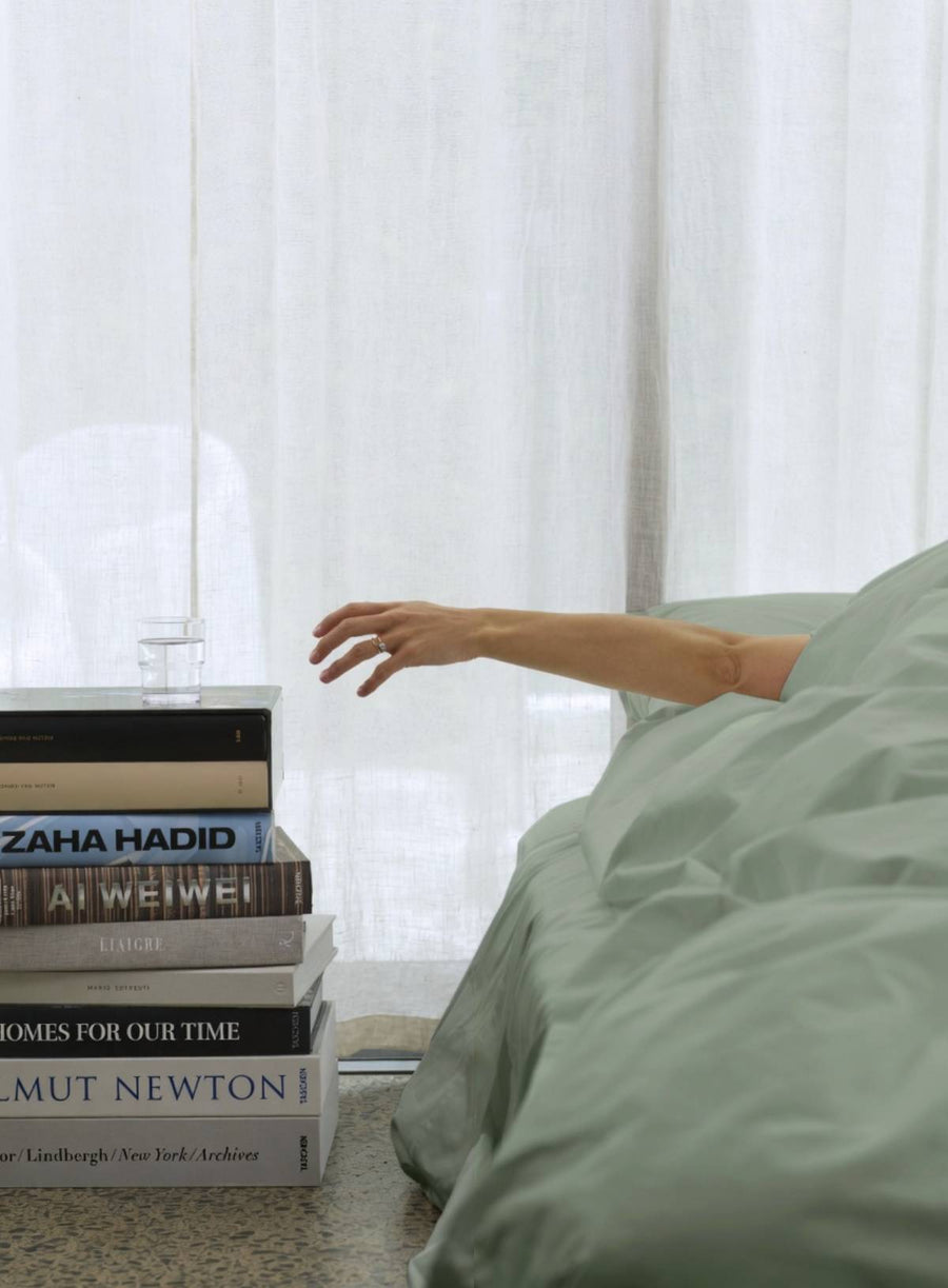 sage duvet cover from house of march with persons arm resachign for glass