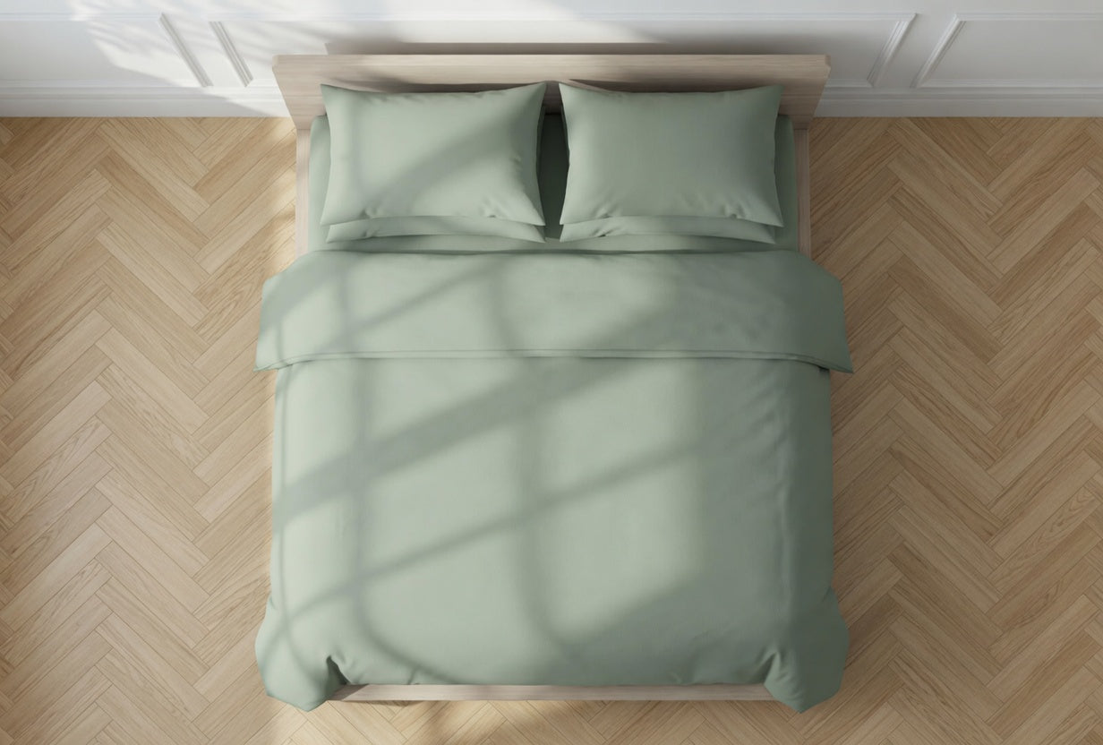 sage Green duvet cover and pillows on a bed with a wooden floor.