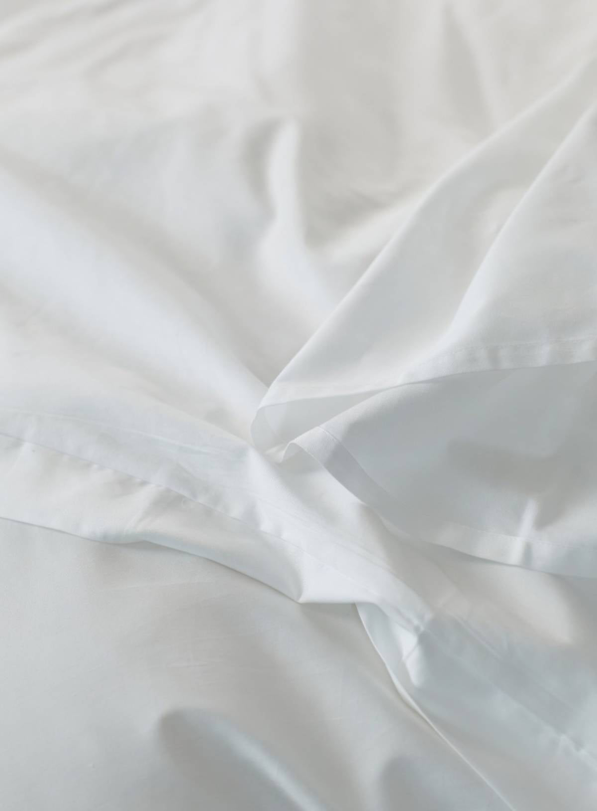 Close-up of white sateen sheet with folds