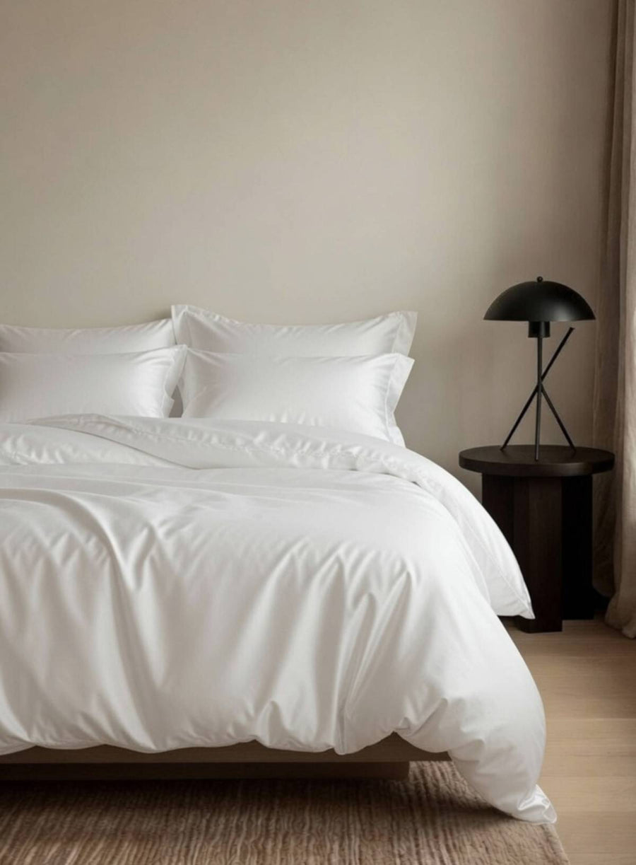 Neatly made bed with white bedding in a minimalistic bedroom setting.